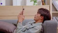 Relaxed Asian man using smart phone surfing internet, update social media, texting message. Techie living with technology devices