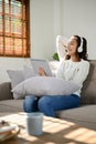 Relaxed Asian woman listening to music through her headphones while chilling on sofa Royalty Free Stock Photo