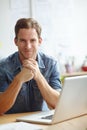 Relaxed attitude at work. A young man sitting at his desk while smiling at the camera. Royalty Free Stock Photo