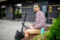 Relaxed attractive young man caucasian sits on bench next to his electric scooter using laptop to work remotely. Freelance and