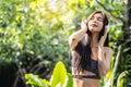 Relaxed beautiful young asian woman breathing deeply fresh air wearing headphones at the park in summer