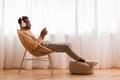 Relaxed Black Man In Headset Using Phone Listening Audiobook Indoor Royalty Free Stock Photo