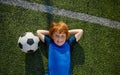 Relaxed boy child little football player rest on grass