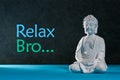Relaxed buddha figurine sitting and meditating, doing yoga exersice. Relax bro - inscription