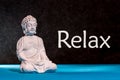 Relaxed buddha figurine sitting and meditating, doing yoga exersice. Relax - inscription