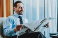 Relaxed businessman reading the newspaper and smiling Royalty Free Stock Photo