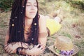 Relaxed and calm indie style woman with dreadlocks hairstyle, lying and resting in the dry grass,