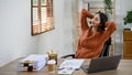 Relaxed Asian businesswoman resting at her desk, eyes closed, leaning on her chair Royalty Free Stock Photo