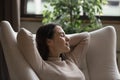 Relaxed calm positive millennial girl resting in comfortable armchair