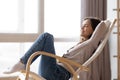 Relaxed calm young woman lounging sitting in comfortable rocking chair