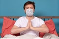 Man in medical mask meditates sitting at home on quarantine, at the bed Royalty Free Stock Photo