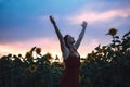 Relaxed and carefree woman in dress standing with arms raised in field of sunflowers during sunset Royalty Free Stock Photo