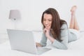 Relaxed casual smiling woman using laptop in bed Royalty Free Stock Photo