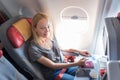 Casual woman flying on commercial passengers airplane, filling in immigration form.