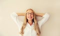 Relaxed caucasian middle-aged woman manager resting with closed eyes and folded hands behind the head in eyeglasses on white wall Royalty Free Stock Photo