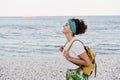 Relaxed caucasian woman with yellow backpack walking by the beach during sunset. summer time. daydreaming. Outdoors lifestyle Royalty Free Stock Photo