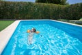Relaxed child with armbands floating in transparent blue water of pool