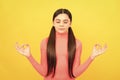 relaxed child with long hair meditating on yellow background, yoga