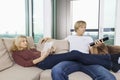 Relaxed couple reading book and watching TV in living room at home Royalty Free Stock Photo