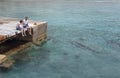 Relaxed couple sitting wooden bridge water