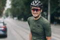 Relaxed cyclist in helmet and glasses posing on empty street