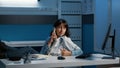 Relaxed doctor sitting with feet on desk table while talking at phone whith remote friend