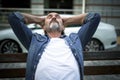 Relaxed, enjoying life handsome middle age man sits leaned back with hands behind his head on the bench outdoors at Royalty Free Stock Photo