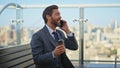 Relaxed entrepreneur talking mobile phone on terrace. Happy bearded man speaking Royalty Free Stock Photo