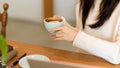 Relaxed female in comfy white sweater drink, sip, hold hot cappuccino coffee cup