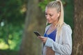 Relaxed fitness woman texting sms on smartphone during a workout break. Royalty Free Stock Photo