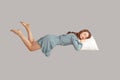 Relaxed girl in vintage ruffle dress levitating in mid-air, sleeping on stomach lying comfortable cozy on pillow