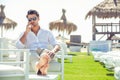 Relaxed handsome man sitting on white chairs during summer Royalty Free Stock Photo