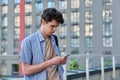Relaxed handsome young male with smartphone, urban outdoor
