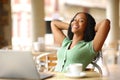 Relaxed happy black woman with laptop resting in a bar Royalty Free Stock Photo