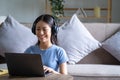 Relaxed happy young teenager Asian woman sitting on sofa using laptop at home, Beautiful cheerful redhead girl using Royalty Free Stock Photo