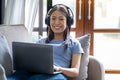 Relaxed happy young teenager Asian woman sitting on sofa using laptop at home, Beautiful cheerful redhead girl using Royalty Free Stock Photo