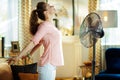 Relaxed housewife enjoying freshness in front of working fan Royalty Free Stock Photo