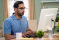 Relaxed Indian freelancer working on computer by drinking coffee at home - concept of refreshment, dedication and