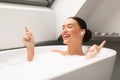 Relaxed Lady With Earbuds Listening To Music Taking Bath Indoors