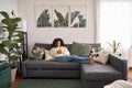 Relaxed latin girl sitting on couch using mobile cell phone at home. Royalty Free Stock Photo