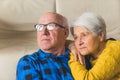 Relaxed loving married elderly man and woman hugging and looking away, wife resting on her husband's shoulder while Royalty Free Stock Photo