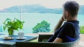 A relaxed man enjoys his lunch break in a hotel cafe terrace with a sea view.