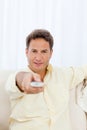 Relaxed man pointing a remote to the camera Royalty Free Stock Photo