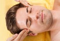 Relaxed man receiving forehead massage in spa