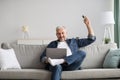 Relaxed man sitting on couch with laptop, turn on AC Royalty Free Stock Photo