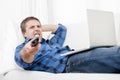 Relaxed man using Computer at home switching tv on Royalty Free Stock Photo