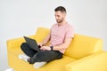 Relaxed man using laptop sitting on yellow sofa over white background Royalty Free Stock Photo