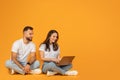 A relaxed man and woman sitting cross-legged on the floor, with the woman using a laptop Royalty Free Stock Photo