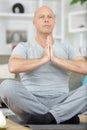 relaxed mature man sitting on yoga mat at home