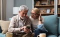 Relaxed mature 60s woman and 70s man older aged senior couple customer holding smart phone using mobile app texting message search Royalty Free Stock Photo